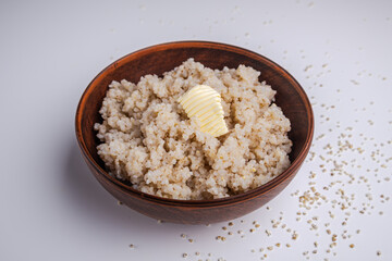 Barley porridge with butter in a clay bowl on a white background