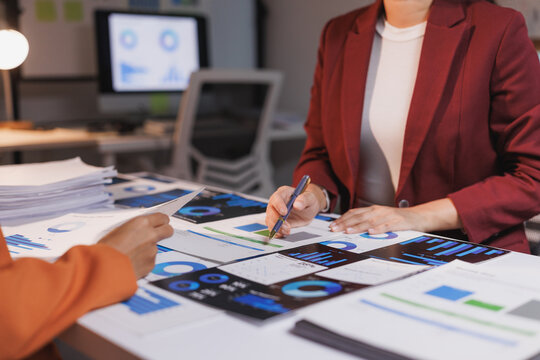 Business professionals analyzing financial data reports late night - Powered by Adobe