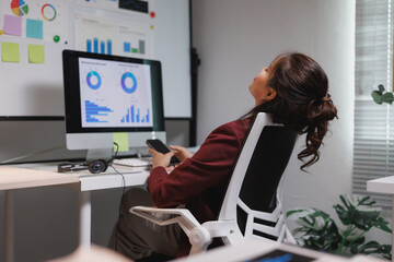 Asian businesswoman relaxing during work break using phone