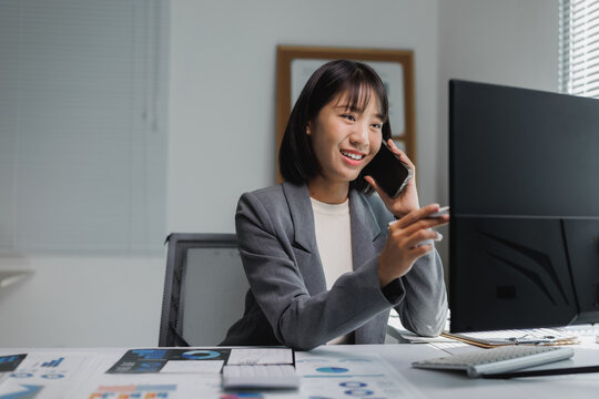 Young businesswoman talking phone checking financial reports