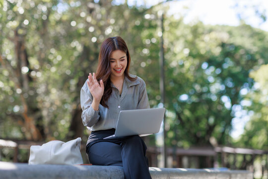 Young woman waving during a video call outdoors - Powered by Adobe