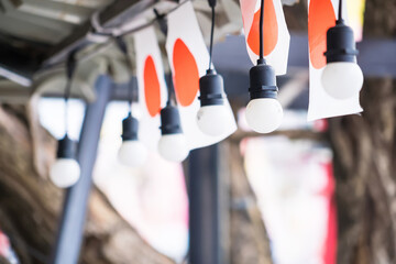 Close-up of hanging light bulbs and Japanese flags used as decorations for a festival or outdoor event