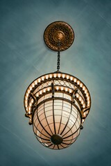 Vintage ornate hanging chandelier with intricate metalwork and warm glowing lights against a textured blue ceiling background