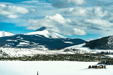 Scenic winter landscape featuring snow-covered mountains and frozen lake under a cloudy sky in a remote natural area