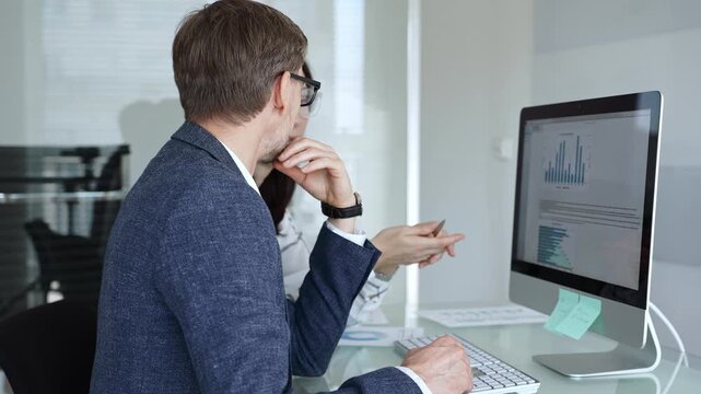 Business colleagues analyzing financial data on computer, discussing project statistics and market trends in office meeting. Businesspeople concept - Powered by Adobe