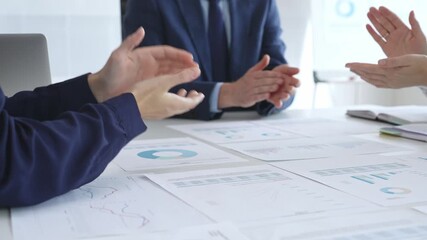 Businesspeople team clapping hands in meeting celebrating success with financial charts, data analysis, sales growth reports, and teamwork achievement in modern office. Business handshake - Powered by Adobe