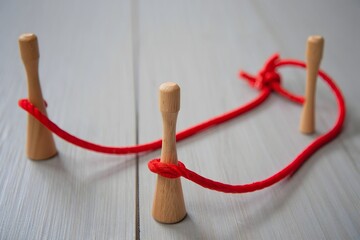 Wooden peg puzzle with red string challenge and solution concept game