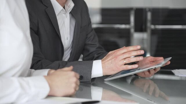 Business people collaborating during a meeting using a modern digital tablet, close up. Discussing strategies and analyzing data in a professional office environment