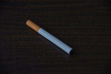 single cigarette on the wooden textured table surface.
