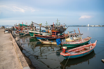 Traditional wooden fishing boats docked in a calm harbor with ropes and nets visible during a peaceful seaside day