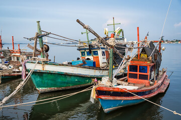 Traditional wooden fishing boats docked in a calm harbor with ropes and nets visible during a peaceful seaside day
