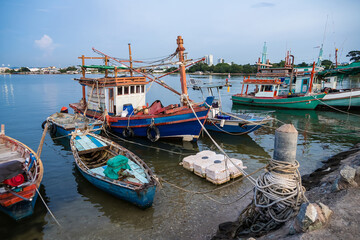 Traditional wooden fishing boats docked in a calm harbor with ropes and nets visible during a peaceful seaside day