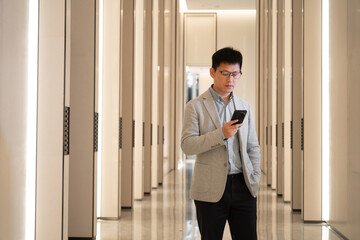 man in a gray blazer uses a phone in a modern lobby