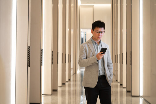 man in a gray blazer uses a phone in a modern lobby