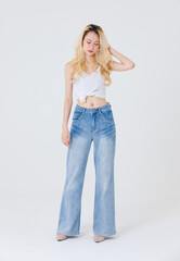 Asian confident beautiful attractive woman blonde long hair stand wear sleeveless top blue jeans on white background studio portrait fashion street outfit trendy style pose look at camera full length.