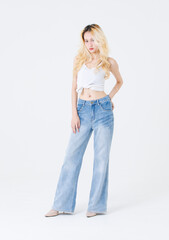 Obraz premium Asian confident beautiful attractive woman blonde long hair stand wear sleeveless top blue jeans on white background studio portrait fashion street outfit trendy style pose look at camera full length.