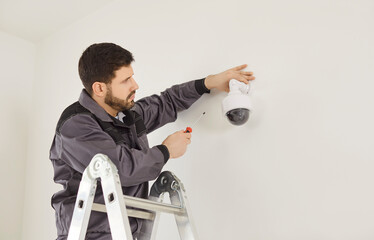 CCTV installation connecting dome security camera, male worker setting up system for viewing...