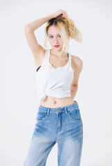 Asian confident beautiful young woman blonde hair high tied  standing wearing sleeveless top jeans on white background studio portrait lifestyle fashion street outfit trendy style pose look at camera.
