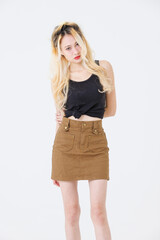 Asian beautiful attractive young woman blonde long hair stand wear black sleeveless top brown short skirt on white background studio, portrait fashion street outfit trendy style pose look at camera.
