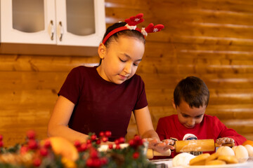 The children are baking Christmas cookies together in the kitchen