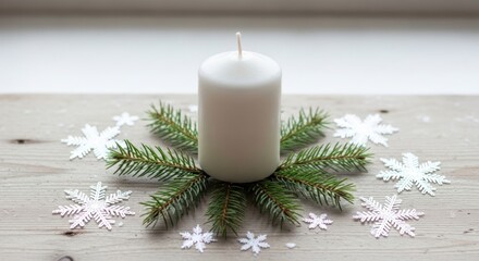 A Christmas candle with fir branches and snowflakes on a wooden table.