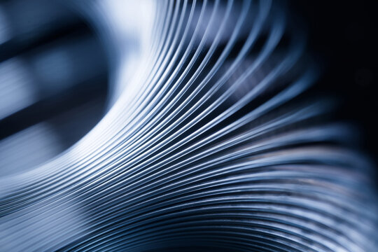 Abstract close-up of curved metallic lines creating a sense of warped space, motion and flowing geometry in cool blue tones. Photo