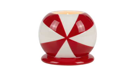 A lit candle glows warmly inside a glossy ceramic holder featuring a festive red and white pinwheel pattern, creating a cozy and decorative ambiance for the holiday season