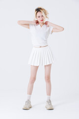 Fototapeta premium Asian confident attractive beautiful woman blonde hair tied stand wear white shirt top mini skirt sport on background studio portrait fashion street outfit trendy style pose look at camera full length