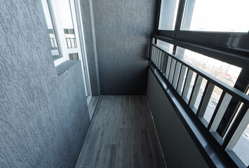 Obraz premium urban balcony featuring glass panels and railing, limited apartment balcony with textured walls and floor, cosy city balcony showcasing modern materials and soft daylight illumination