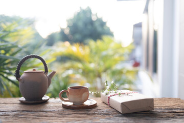 Old earthenware tea pot and gift box with flower on balcony outdoor in winter under