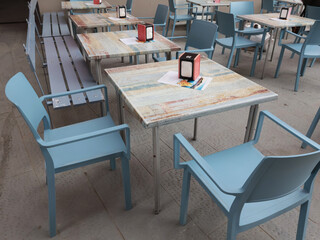 Tables and chairs in street cafe. Traditional buildings and historic center. Furniture design.