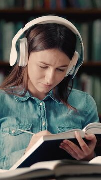 Student reads a book and takes notes in a library focused on learning new information