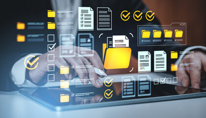 Businessman using digital tablet with virtual folder and document icons representing data management and file organization concept on dark background.