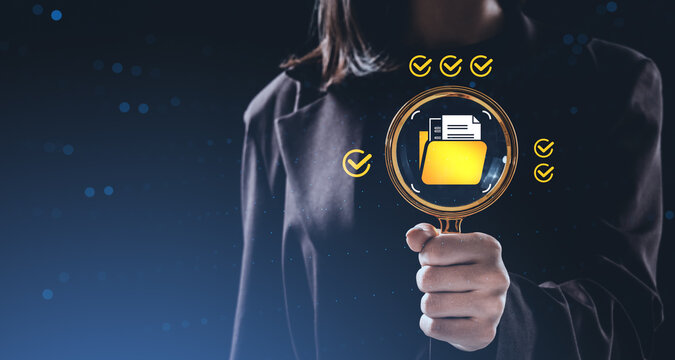 Businesswoman holding magnifying glass with digital folder and documents icon on creative background representing data search and document management concept.
