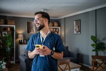 Male healthcare worker smiling, holding phone at home