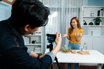 Asian beautiful woman food specialist presenting healthy meal wholegrain bun bread basket on live channel recorded video camera by smart cameraman streaming lifestyle social media online. Infobahn.