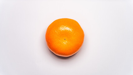 A single, perfectly round orange is photographed from directly above on a clean, solid white background. The lighting is bright and even.