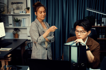 Businesswoman pointing report data analysis overworked project job folder paperwork with stressful coworker to continue working at over late night time at modern office on overtime company. Infobahn.