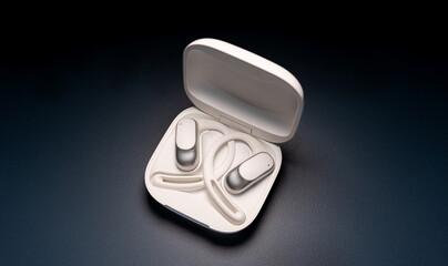 Modern wireless open-ear headphones resting in their sleek charging case.