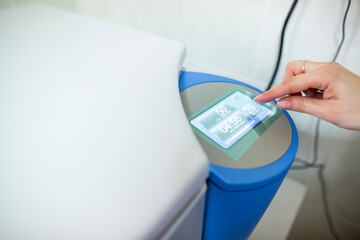 Close up view of a scientist hand pressing the touchscreen control panel of a modern electronic laboratory centrifuge device setting the timer and speed for sample preparation process