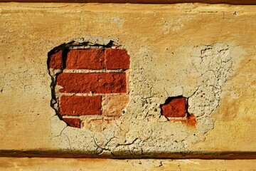Mur abimé troué avec briques rouges apparentes.
