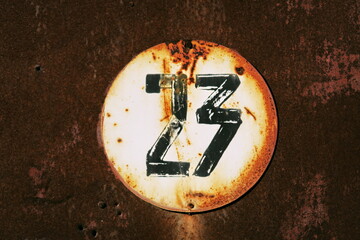 Vingt trois. Numéro 23. Plaque de numéro de rue sur fond rouillé.