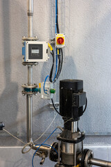 A black industrial water pump and a digital flow meter are part of a modern fluid control system....