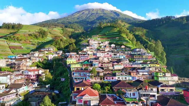 Aerial clip featuring a dense mountain settlement surrounded by terraced fields and natural scenery. Nepal Van Java Village, Mount Sumbing, Indonesia.