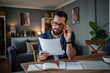 Male doctor studying medical paperwork at home after hours