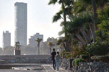 Couple walking on pavement near palm trees in Limassol, Cyprus