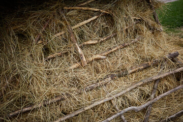 Layers of hay and sticks create a rustic texture in a farmyard during a sunny afternoon in late...