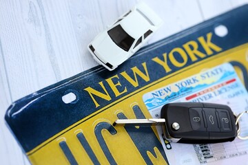 Remote control car keys on New York license plate with driver license. Concept of driving in New York. Reaching a driving permit