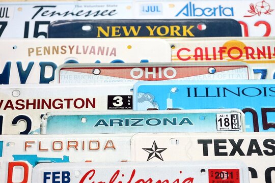 Old US car license plates with various state names. Concept of driving in United States. Reaching a car registration