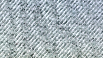 close-up photograph of light gray blue herringbone weave fabric texture showing detailed fuzzy...